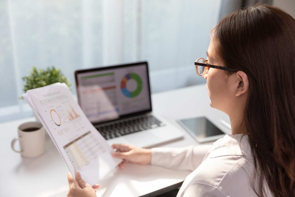 A female HIM analyses information printed on paper and shown on a computer screen